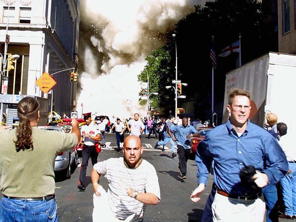 Pedestrians running from the scene as one of the towers collapses. Picture: Doug Kanter/AFP