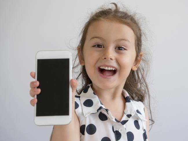 Cute little girl showing mobile phone screen, studio shot. Children with smartphones generic