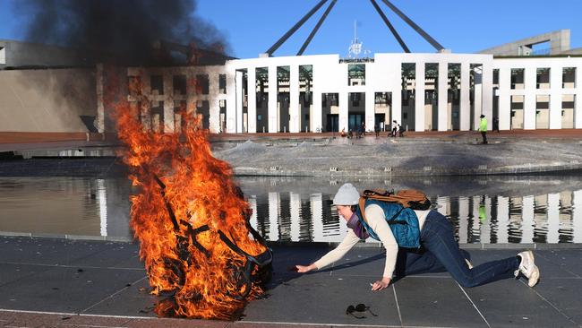 Extinction Rebellion protesters attack the front of Parliament House, Canberra, lighting a baby's pram and gluing their hands to the forecourt, on August 9. Picture: NCA NewsWire / Gary Ramage