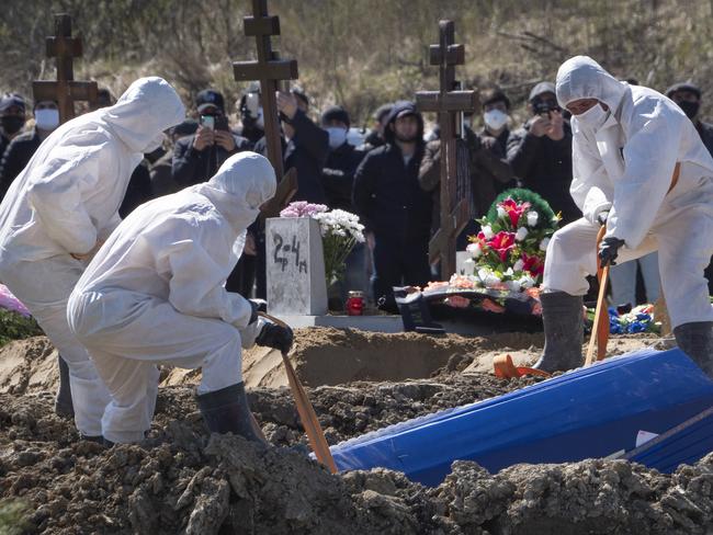 Gravediggers bury a COVID-19 victim as relatives and friends stand at a safe distance near St Petersburg. Picture: AP