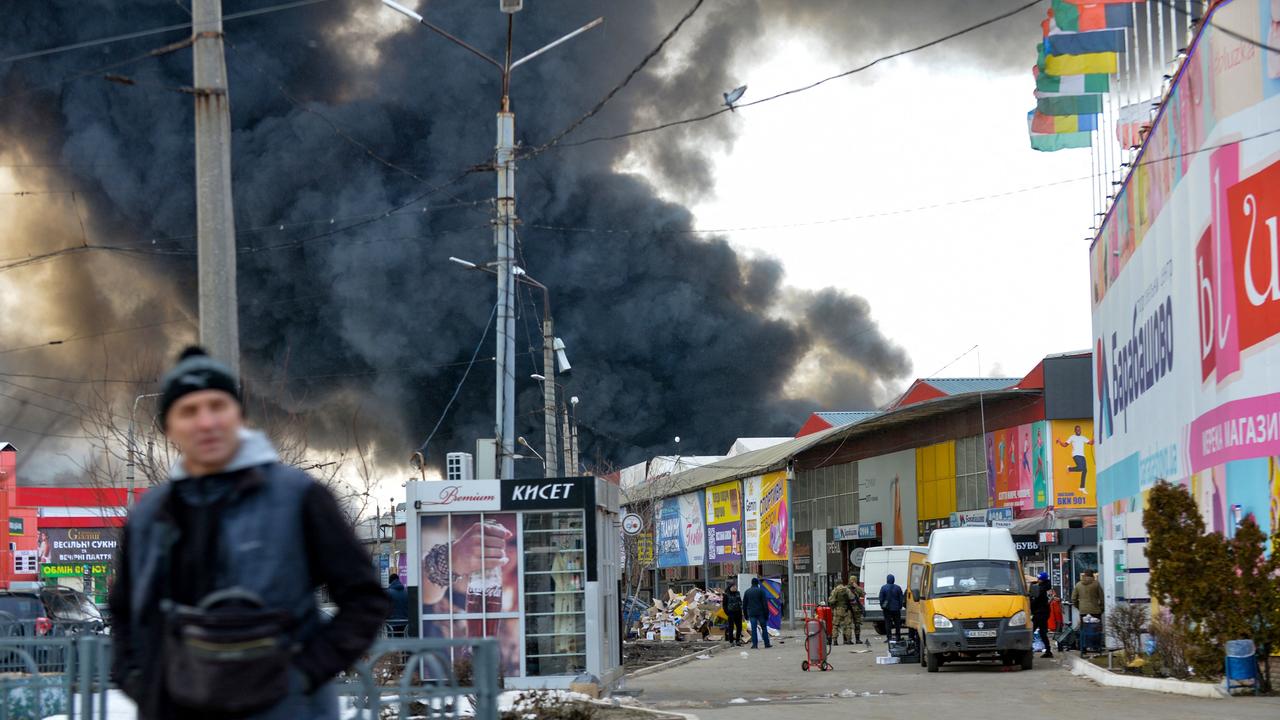 A Ukrainian man look on as thick black smoke rises into the sky behind him from the Barabashovo market in Kharkiv. Picture: Sergey Bobok/AFP