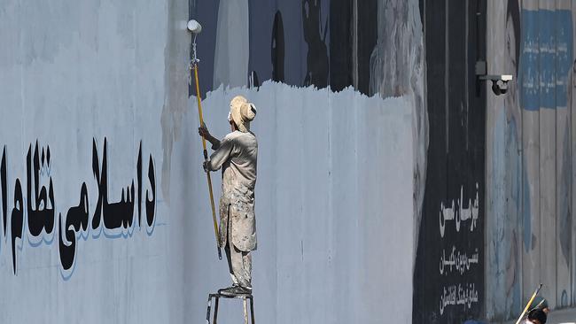 A man paints over murals on a concrete wall along a street in Kabul. Picture: AFP