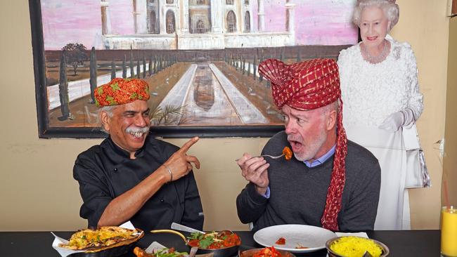 Manly Daily reporter Jim O'Rourke (centre) takes another bite of the super spicy Platinum Jubilee Chicken Curry created by chef, and owner of the Ashiana Indian Restaurant in Manly, Rajesh Kalra (left), as Her Majesty Queen Elizabeth II (right) gives her royal approval. Picture: Max Agency