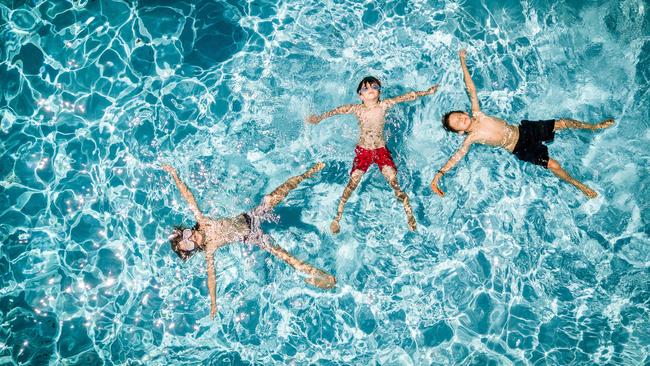 Felix, 10, Oliver, 7 and Remi, 7 practice floating on their backs in a backyard pool. Picture: Jake Nowakowski