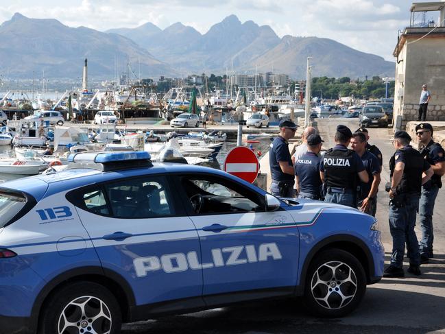 Italian police officers stand at the port as the search continues for six passengers missing from a sailboat that sank off the coast of Porticello, northwestern Sicily. Picture: AFP