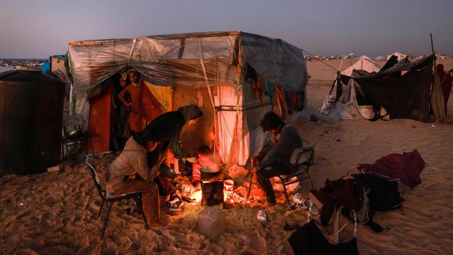 Displaced Palestinians prepare an iftar meal, the breaking of fast, on the first day of the Muslim holy fasting month of Ramadan, outside a tent in Rafah in the southern Gaza Strip on March 11.