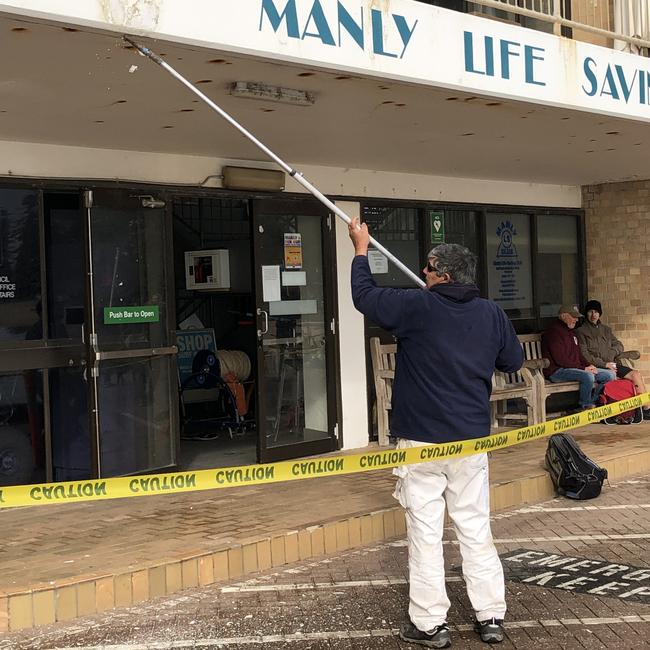 A contractor preparing the outside of the Manly Life Saving Club for a coat of paint in August, 2022. Picture: Jim O'Rourke