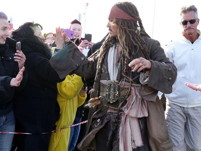 Johnny Depp surrounded by security high-5’s a fan before leaves on a boat to be ferried out to Moreton Bay to continue filming Pirates of the Caribbean. Picture: Liam Kidston