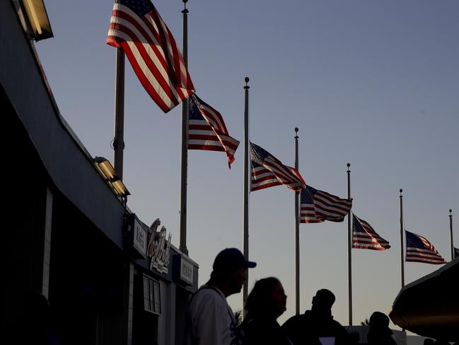 Fans arrive under flags that have been lowered to half staff in respect for the victims of the Las Vegas shootings, before Game 1 of a baseball National League Division Series between the Arizona Diamondbacks and the Los Angeles Dodgers in Los Angeles, Friday, Oct. 6, 2017. (AP Photo/Jae C. Hong)