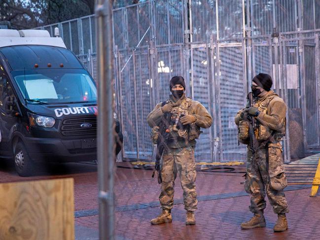 Members of the National Guard stand behind a barbed wire fence perimeter surrounding the Hennepin County Government Centre. Picture: AFP