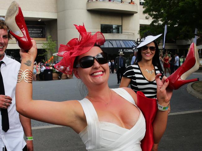 Crowd at Rosehill races in Sydney on Melbourne Cup day. A girl takes off her shoes as she leaves the racecourse.