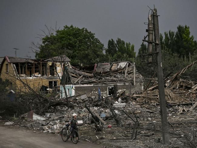 An ederly woman with her bicycle walks next to debris of destroyed houses after a strike in the city of Dobropillya at the eastern Ukrainian region of Donbas. Picture: AFP