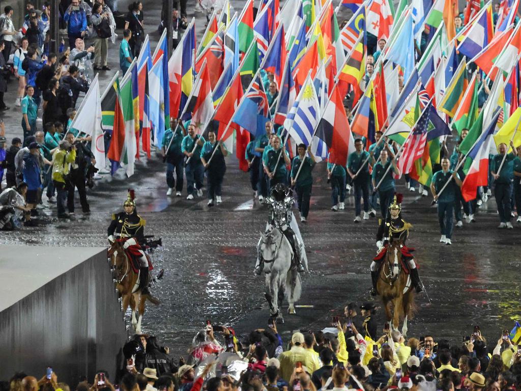 Floriane Issert, a Gendarmerie non-commissioned officer of the National Gendarmerie, carries the Olympic flag as she rides on the Iena bridge during the opening ceremony of the Paris 2024 Olympic Games in Paris on July 26, 2024. (Photo by Ludovic MARIN / POOL / AFP)