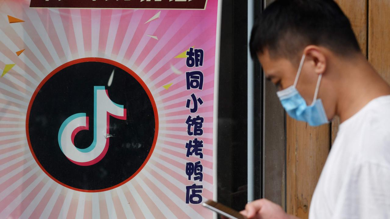 A man walks past a restaurant with a TikTok logo displayed in the window in Beijing. The US has ordered a ban on downloads of two major Chinese-owned apps, saying they threaten national security. Picture: GREG BAKER / AFP.