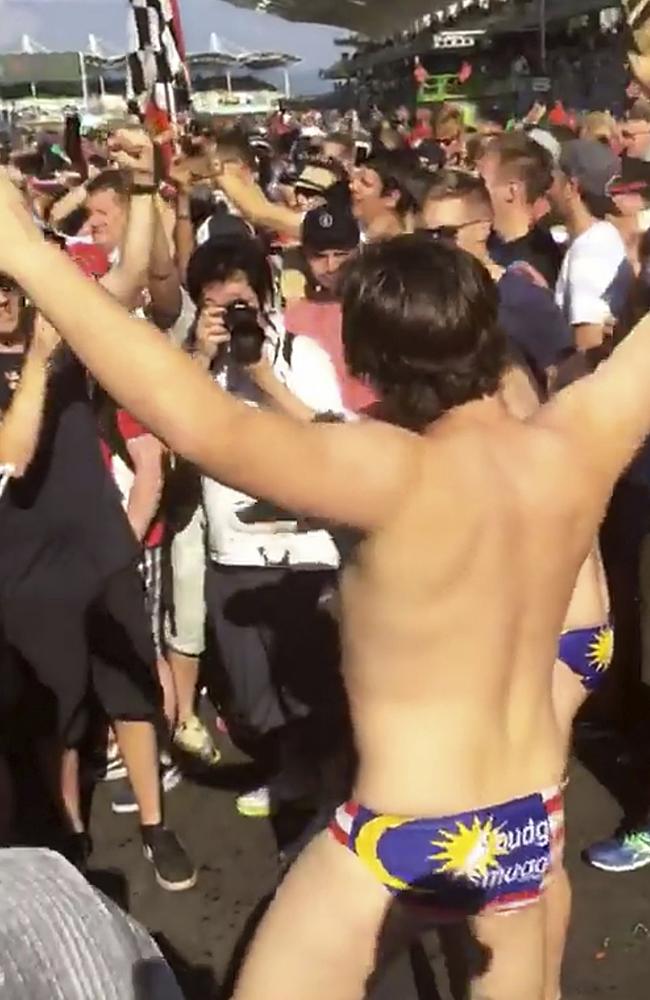 One of the Australian men dances in Budgy Smuggler-brand swimsuits decorated with the Malaysian flag at the conclusion of the Malaysian Formula One Grand Prix in Sepang. Picture: From video by Umar Akif Jamaludin.