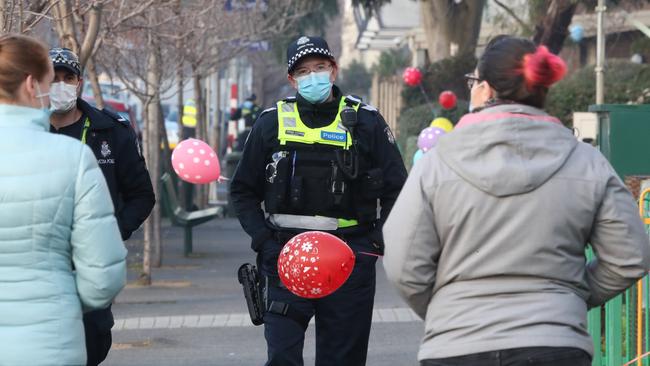 Police walk past balloons tied to the fence at the North Melbourne towers. Picture: David Crosling