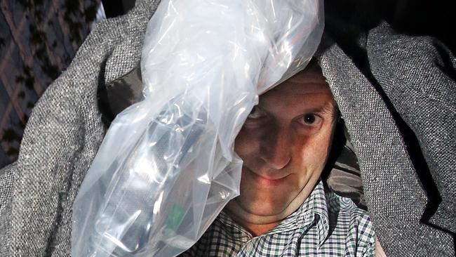 Richard Vucinic tries to shelter from photographers as he leaves the Melbourne Magistrates’ Court. Picture: Alex Coppel.