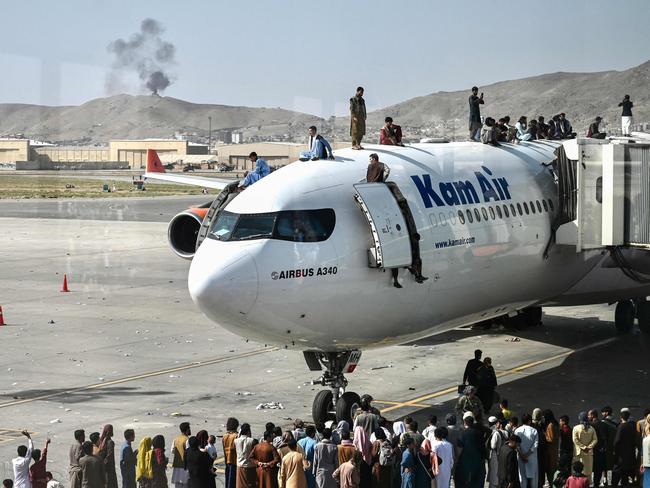 Afghan people climb atop a plane as they wait at the Kabul airport in Kabul on August 16 after a swift end to Afghanistan's 20-year war, as thousands of people mobbed the city's airport trying to flee the group's feared hard line brand of Islamist rule. Picture: Wakil Kohsar/AFP