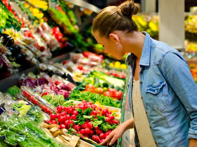 A young blond woman in the supermarket is looking for some fruits generic istock