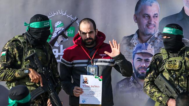 Palestinian militant group Hamas fighters escort Israeli hostages Yarden Bibas on a stage before handing him over to a Red Cross team in Khan Yunis.