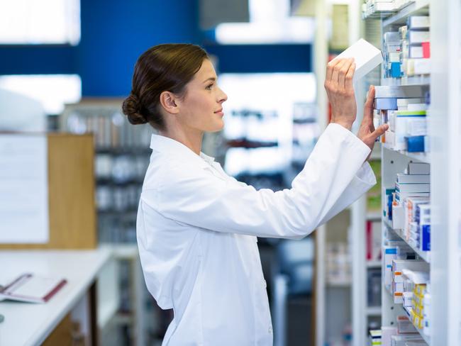 Pharmacist checking medicine in shelf at pharmacy