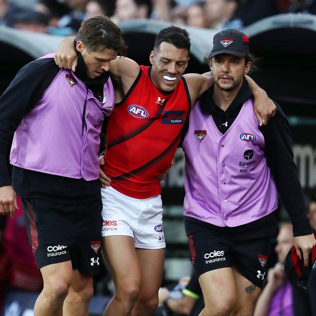 Bomber Dylan Shiel is helped off the field in the hands of trainer. Picture: Getty Images