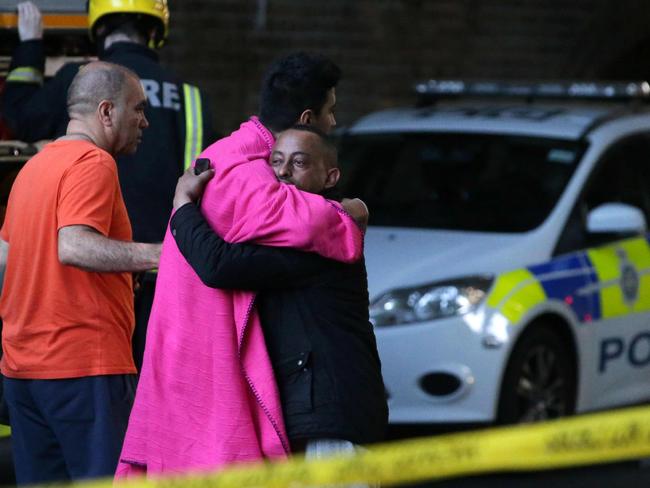 Two survivors hug within the security cordon as Grenfell Tower. Picture: AFP