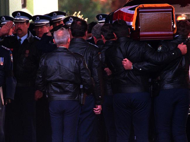 Senior police officers salute as the coffin of Senior Sergeant Ray Smith is carried during procession at his funeral service.