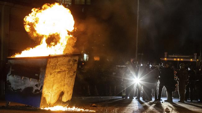 Tucson Police Department officers guard firefighters approaching a dumpster lit on fire. Picture: Josh Galemore