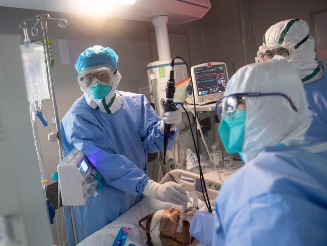 TOPSHOT - Medical staff treat a COVID-19 coronavirus patient at a hospital in Wuhan, in China's central Hubei province on March 19, 2020. - China on March 19 reported no new domestic cases of the coronavirus for the first time since it started recording them in January, but recorded a spike in infections from abroad. (Photo by STR / AFP) / China OUT