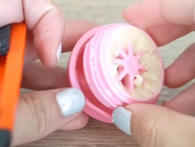 Using a knife or spoon, pop out the base of the Revo balm to ensure you can get all of the product out of the container. Picture: Youtube/Cute Life Hacks