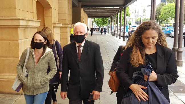 Michael William Wall, centre, flanked by his lawyer Rachael Shaw, right, and one of his nieces, left, as he leaves the District Court. Picture: Sean Fewster.