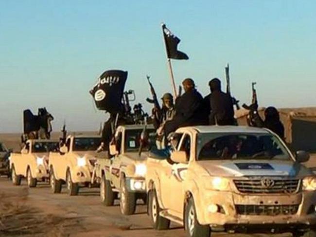 FILE - In this undated file photo released by a militant website, which has been verified and is consistent with other AP reporting, militants of the Islamic State group hold up their weapons and wave flags as they ride in a convoy, which includes multiple Toyota pickup trucks, through Raqqa city in Syria on a road leading to Iraq. Toyota is working with U.S. officials after questions were raised about the prominent use of its vehicles by militant organizations in Syria, Iraq and Libya. (Militant website via AP, File)