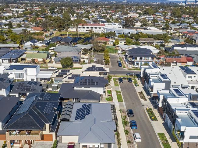 Aerial view looking down on new, modern Adelaide housing development with mixed house & architectural styles: single level houses, townhouses, construction site, green space, established suburb & city in background. Picture: iStock/BeyondImages