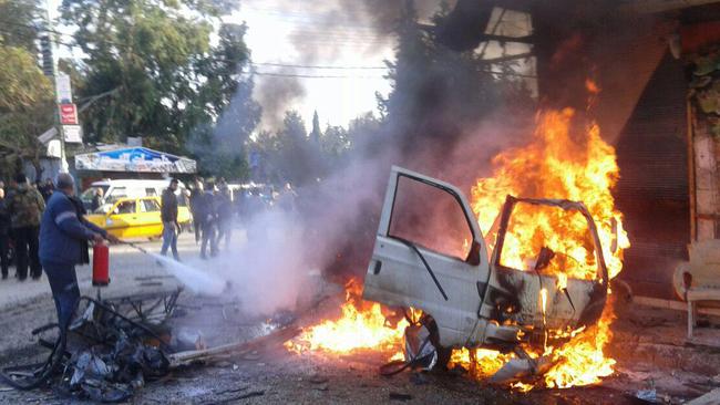 This handout image made available by the official Syrian Arab News Agency (SANA) on January 22, 2019, shows onlookers and security forces gathered around a burning vehicle in the city of Latakia.