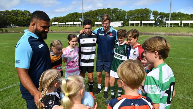 Waratahs players Tolu Latu and Cameron Clark with juniors at Brookvale Oval.