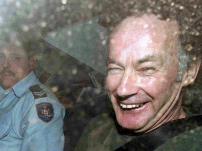 Ivan Milat smiles in a police car after attending a court in 1997.