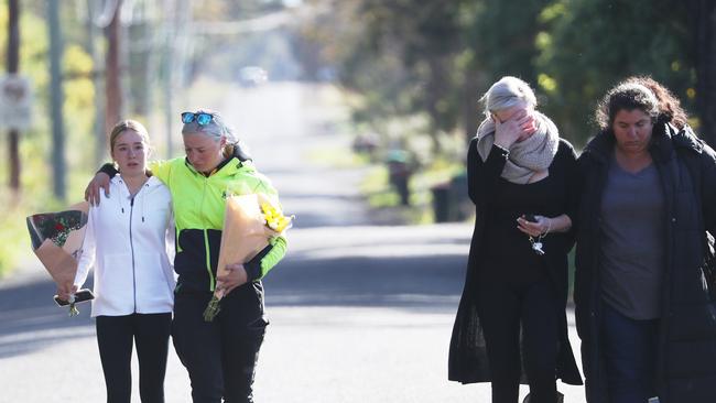 Heartbroken friends make their way to the scene of a fatal crash to lay flowers. Picture: John Grainger/Daily Telegraph