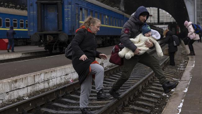 A family crosses the railway line in Lviv as they flee Ukraine. Picture: Getty Images