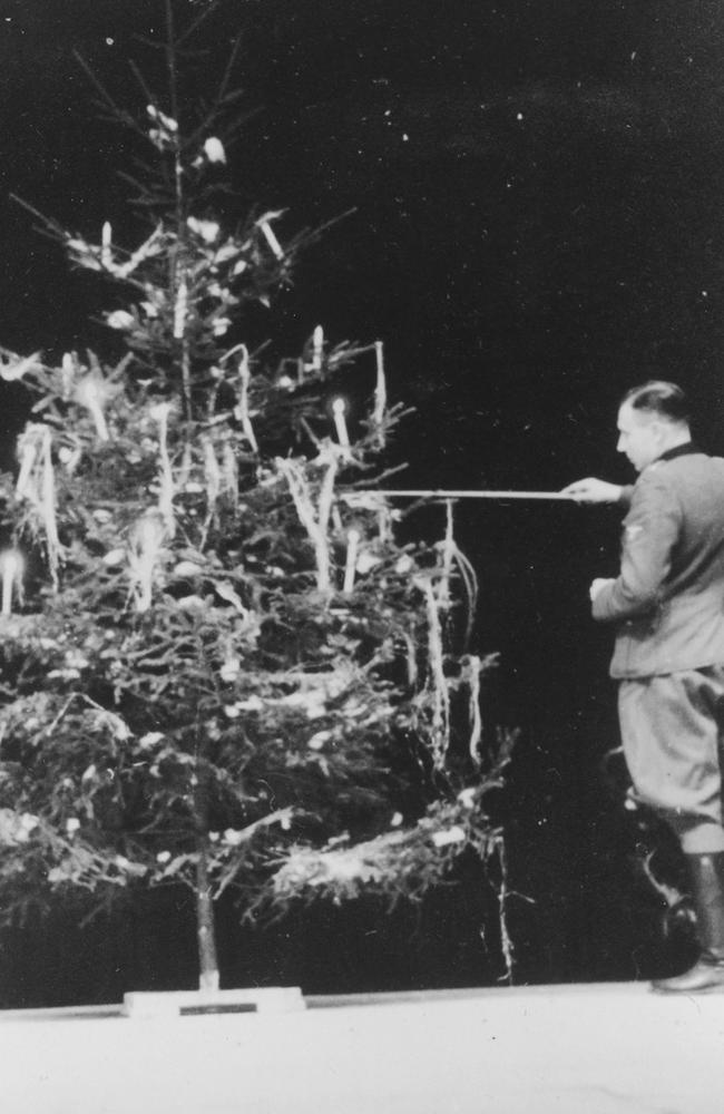 SS officer Karl Hoecker lights a candle on a Christmas Yule tree. Picture: United States Holocaust Memorial Museum