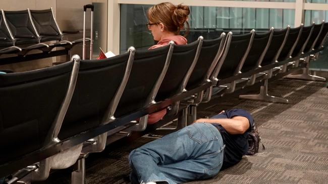 DETROIT, MICHIGAN - JULY 20: Travelers rest where they can in the McNamara terminal at the Detroit Metropolitan Wayne County Airport on July 20, 2024, in Detroit, Michigan. Many travelers were rerouted or had their flights canceled as the world continues to be affected by a global technology outage attributed to a software update administered by CrowdStrike, a cybersecurity firm whose software is used by various industries worldwide.   Joe Raedle/Getty Images/AFP (Photo by JOE RAEDLE / GETTY IMAGES NORTH AMERICA / Getty Images via AFP)