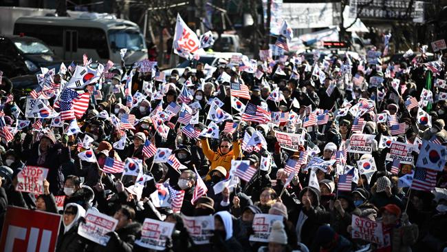 People wave US and South Korean flags during a rally in support of Mr Yoon in the Gwanghwamun area of Seoul on Friday. Picture: AFP