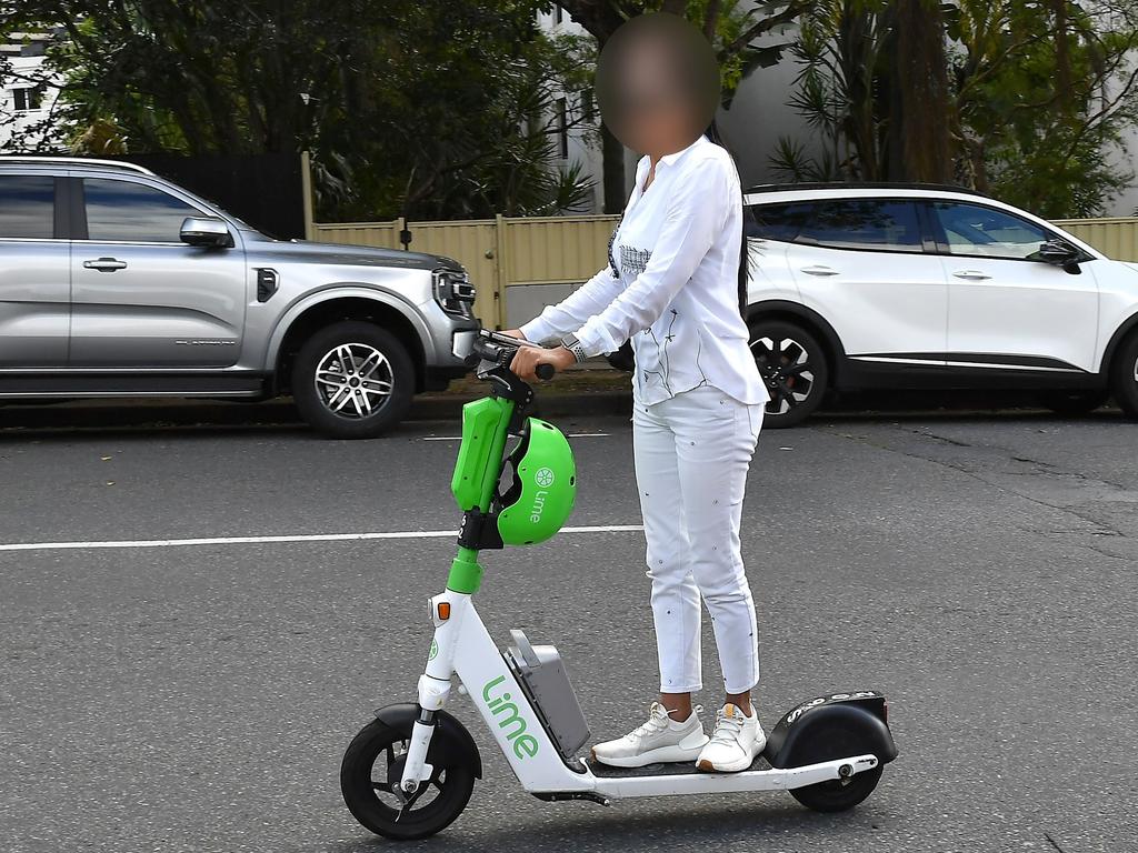 An e-scooter rider in Brisbane with their helmet still attached to the scooter. Picture: John Gass