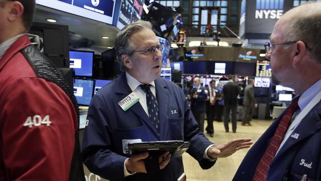 Traders Thomas Kaye, center, and Frederick Reimer confer on the floor of the New York Stock Exchange, Tuesday, Dec. 1, 2015. Stocks are slightly higher in early trading as investors look ahead to a busy week of economic reports and central bank meetings. (AP Photo/Richard Drew)