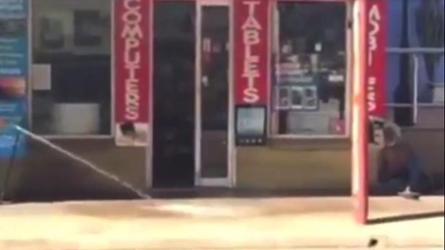 Shop owner sprays water at an Aboriginal man outside his business