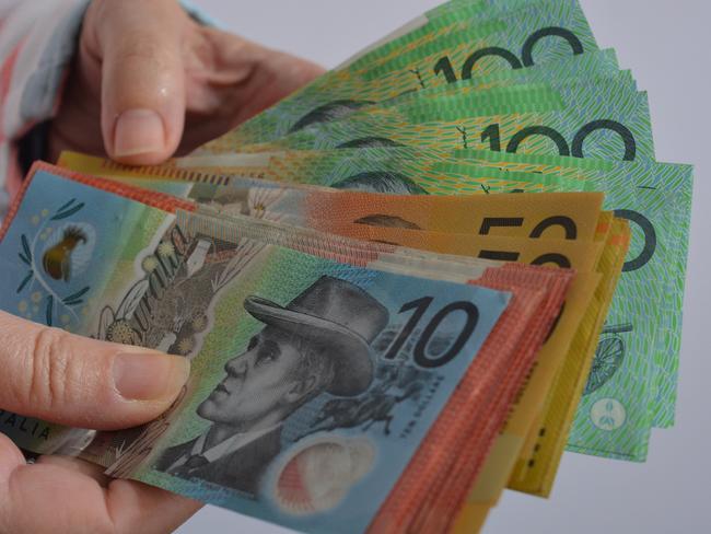 Various denominations of Australian dollars, including $100, $50, $20 and $10 banknotes in a person's hands