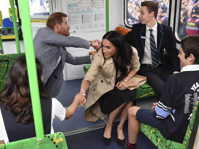 Britain's Prince Harry and his wife Meghan, Duchess of Sussex shake hands with local schoolchildren as they take a ride on a tram in Melbourne. Picture: AFP