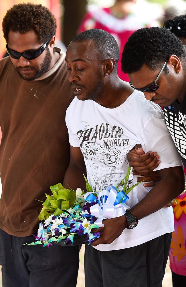 Gavin Willie (centre), father of three of the victims, is supported at a makeshift memorial yesterday. Pic: Ian Hitchcock/Getty