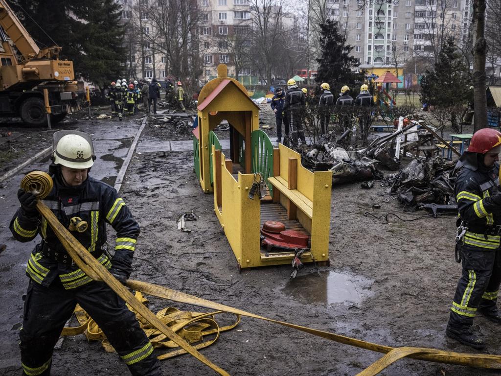 Firemen roll up hoses in front of debris as emergency service workers respond at the site of a helicopter crash. Picture: Getty Images