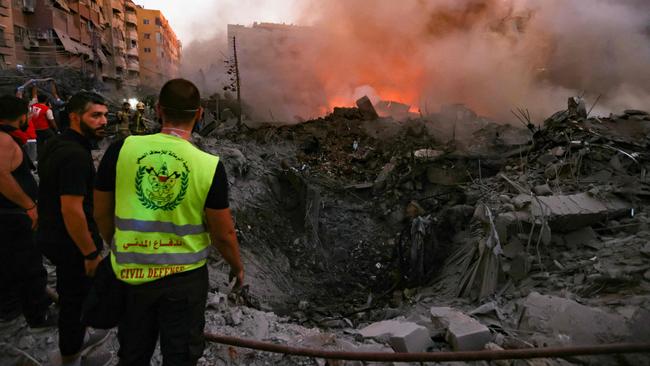 People and rescuers gather near the smouldering rubble of a building destroyed in an Israeli air strike in the Haret Hreik neighbourhood of Beirut's southern suburbs. Picture: AFP